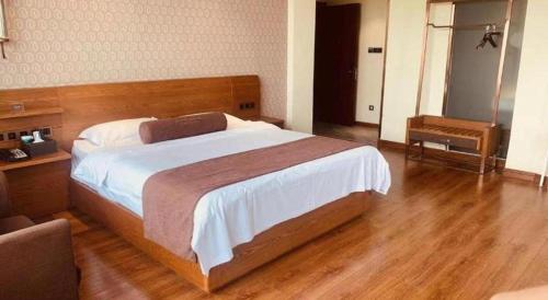 a bedroom with a large bed and a wooden floor at James Joyce Coffetel Qufu Tourist Center Gulou Street Sankong Scenic Spot in Jining