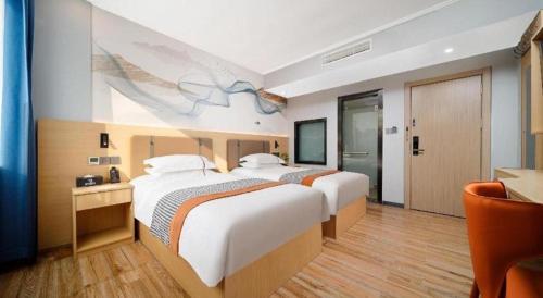 two beds in a hotel room with a painting on the wall at JIAN AI XI YUE HOTEL in Yiwu