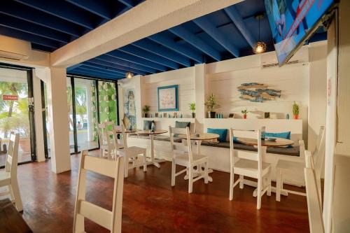 a dining room with white chairs and tables and blue ceilings at Penthouse Beachfront Luxury Bay View - West End in Roatan