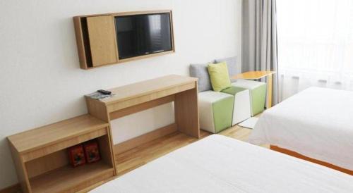 a room with a bed and a tv and a couch at 7Days Inn Tianjin Airport NO.1 Bridge Branch in Tianjin