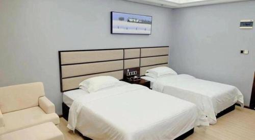 a hotel room with two beds and a chair at Li An Hotel Shantou Xiashan Central Bus Station Branch in Shantou