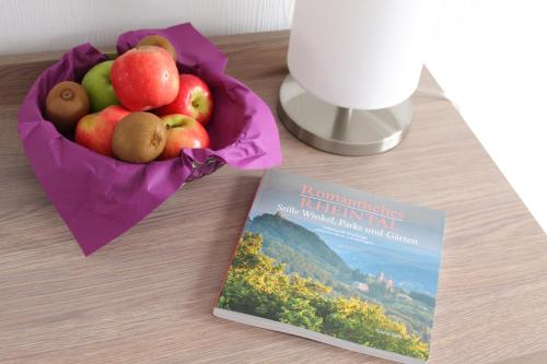 a book next to a bowl of fruit next to a book at RheinHotel ARTE in Remagen
