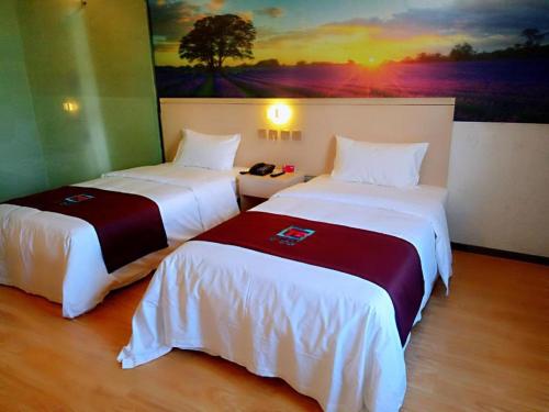 two beds in a room with a painting on the wall at PAI Hotels·Urumqi South Gate Xinhua Bookstore in Ürümqi