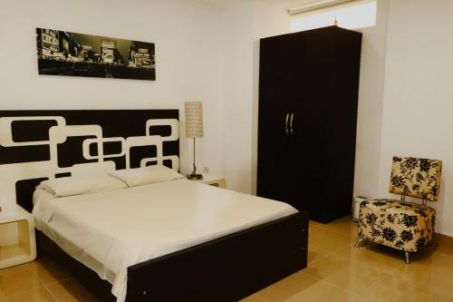 a bedroom with a bed and a black cabinet and a chair at Hotel Portobelo Guatape in Guatapé
