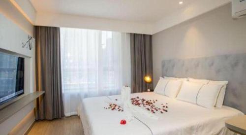 a bedroom with a large white bed with flowers on it at Magnotel Harbin Songbei Wanda Wenlvcheng in Harbin