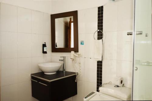 a bathroom with a sink and a toilet and a mirror at Hotel Portobelo Guatape in Guatapé