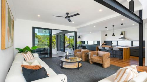 ein offenes Wohnzimmer mit weißen Möbeln und einer Küche in der Unterkunft Aquilae-Waterfront Property Horsfield Bay -firepit,late check out in Blackwall