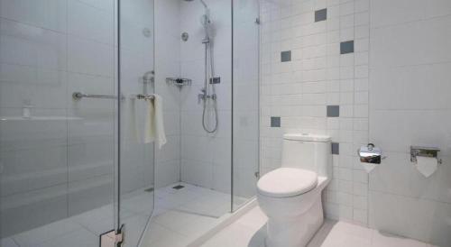 a white bathroom with a shower and a toilet at Magnotel Hotel Jining Yanzhou Metro Station Jiuxianqiao South Road in Jining