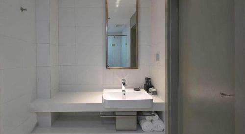 a white bathroom with a sink and a mirror at Magnotel Hotel Jining Yanzhou Metro Station Jiuxianqiao South Road in Jining