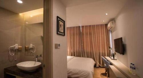 ein Badezimmer mit einem Bett und einem Waschbecken in einem Zimmer in der Unterkunft Borrman Hotel Hefei Guogou Plaza Sanli'an Metro Station in Hefei