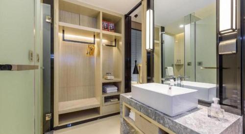 a bathroom with a sink and a large mirror at Echarm Hotel Nanning Baisha Avenue Tingjiang Interchange BBK in Nanning