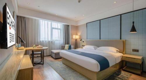 a hotel room with a large bed and a desk at Echarm Hotel Nanning Chaoyang Square River View in Nanning