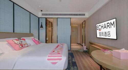 a bedroom with a large white bed and a table at Echarm Hotel Nanning Chaoyang Square River View in Nanning