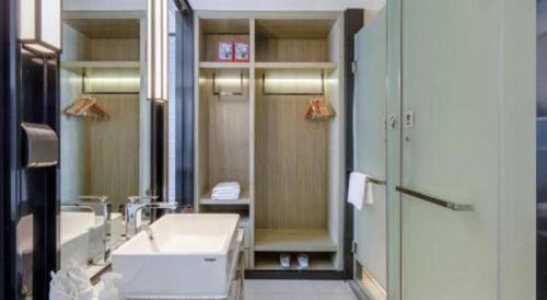 a bathroom with a sink and a shower and a mirror at Echarm Hotel Nanning Chaoyang Square River View in Nanning