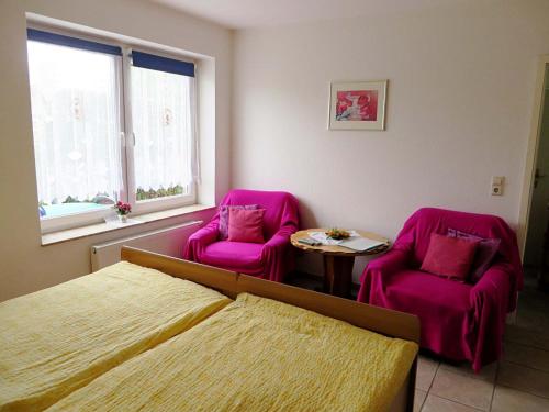 a bedroom with two pink chairs and a table at Ferienwohnungen "Marie" mit Terrassen, inclusive Park- und Stellplätze am Haus, Müritz-Strand nur 700m, Altstadt 10min, ruhige Lage, in Waren