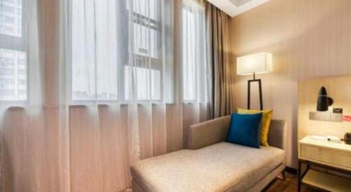 a living room with a couch and a window at Echarm Hotel Jingjiang Bus Passenger Station Fanggu Street in Jingjiang