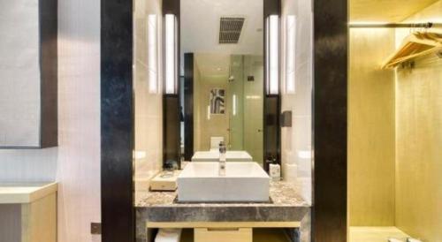 a bathroom with a sink and a large mirror at Echarm Hotel Jingjiang Bus Passenger Station Fanggu Street in Jingjiang