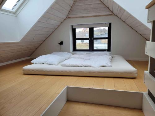 ein großes Bett in einem Zimmer mit Fenster in der Unterkunft Beachfront Cottage With Panoramic View in Lønstrup
