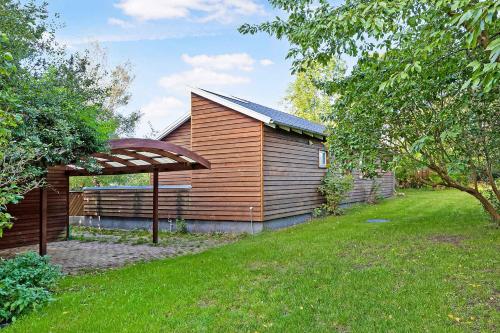 a wooden house with a grassy yard in front of it at Scenic Summer House 600 Meters From Sandy Beach in Asnæs