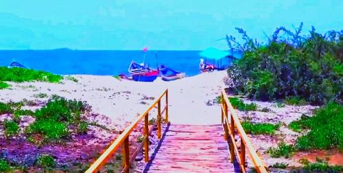 a wooden bridge leading to a sandy beach with boats at Samant Beach Resort in Malvan
