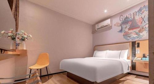 a bedroom with a large white bed and a chair at City Comfort Inn Liuzhou High-speed Railway Station in Liuzhou