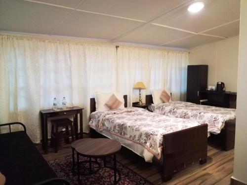a hotel room with two beds and a table at Montevideo Boutique Homestay in Shillong