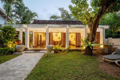 a house with a courtyard with a tree at Wasantha Garden Hotel Restaurant & Ayurvedic Treatment in Weligama