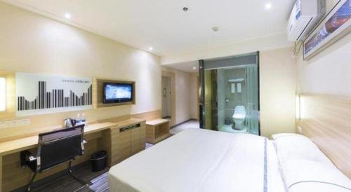 a hotel room with a bed and a desk and a tv at City Comfort Inn Wuhan Zhongnan Road Metro Exit in Wuhan