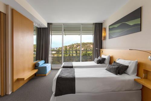 a hotel room with two beds and a large window at Chateau Royal Beach Resort & Spa, Noumea in Noumea
