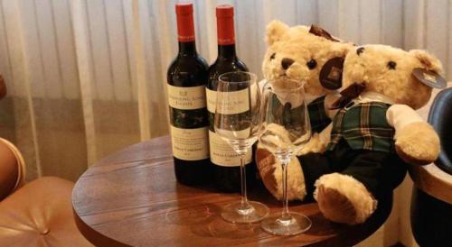 a teddy bear and two bottles of wine on a table at James Joyce Coffetel Shijiazhuang the Mixc Jinyuan Tower Airport Bus in Shijiazhuang