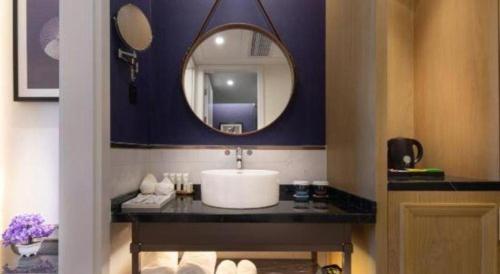 a bathroom with a sink and a mirror at Jinjiang Metropolo Haikou East High Speed Railway Station Normal University in Haikou