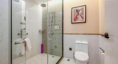 a bathroom with a toilet and a glass shower at Jinjiang Metropolo Haikou East High Speed Railway Station Normal University in Haikou