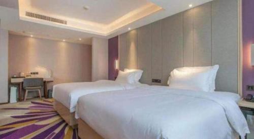 a hotel room with two beds and a desk at Lavande Hotels Wuhan Guanggu Yangjiawan Metro Station in Wuhan
