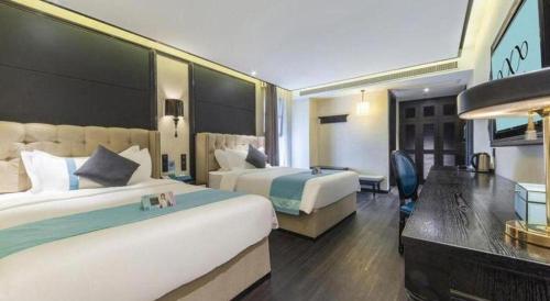 a hotel room with two beds and a desk at Xana Hotelle Nanchang Tengwang Pavilion Wanshougong in Nanchang
