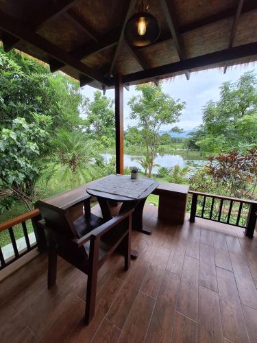 a porch with a table and a view of a river at Le-Mao Chiang Dao in Chiang Dao