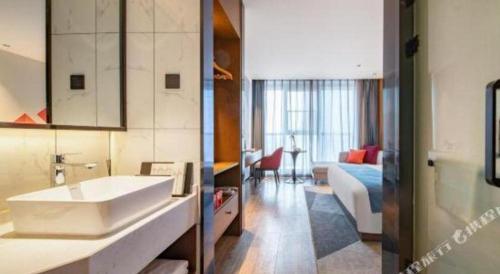 une salle de bain avec lavabo et un salon dans l'établissement Borrman Hotel Ji'nan Aoti Center East Provincial Hospital, à Jinan