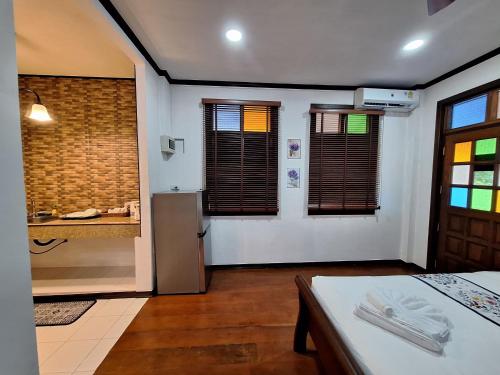 a room with a kitchen with a table and a refrigerator at Le-Mao Chiang Dao in Chiang Dao