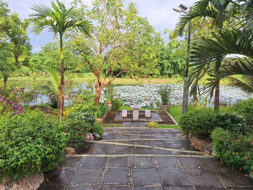 a garden with a stone walkway next to a pond at Le-Mao Chiang Dao in Chiang Dao