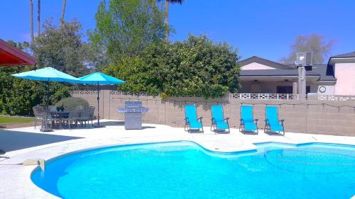 a swimming pool with blue chairs and an umbrella at House & Private Pool, Fast Wifi, Great Location! in Scottsdale