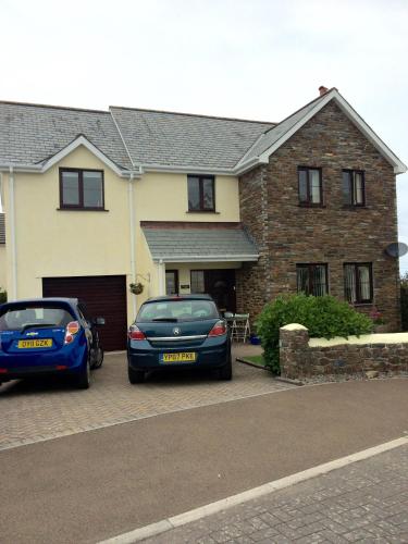 two cars parked in front of a house at Home from Home B&B in Hartland