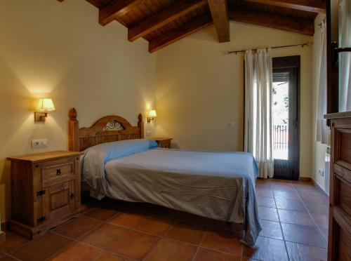 a bedroom with a bed and a dresser and a window at Alojamientos Rurales Hurdes Altas in Casares de las Hurdes