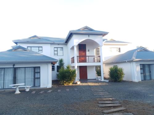 a white house with a driveway in front of it at Mountain View Guest House in Underberg- House in Underberg
