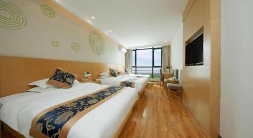 a hotel room with two beds and a television at Green Tree Inn Fengxian New City Metro Station Jiukeshu Art Center in Shanghai