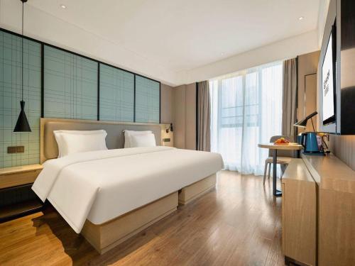 a bedroom with a large white bed and a television at Echarm Hotel Nanning the MixC Dongmeng Business District in Nanning