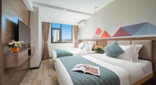 a hotel room with two beds with a book on it at Borrman Hotel Yuxi Yuxing Road in Yuxi