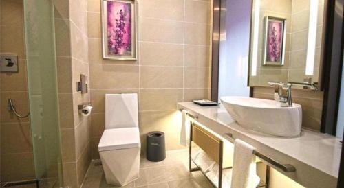 a bathroom with a sink and a toilet and a mirror at Lavande Hotel Huizhou Shiwan in Huizhou