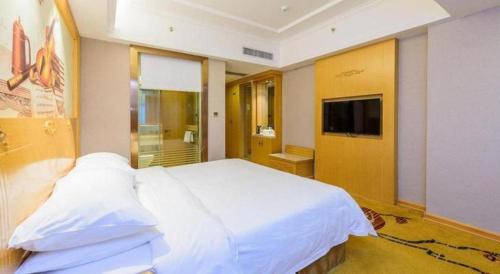 a bedroom with a large white bed and a television at Vienna Hotel Guangxi Fangcheng in Fangcheng