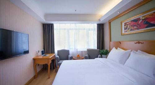 a hotel room with a large bed and a television at Vienna Hotel Inner Mongolia Tongliao Development Zone in Tongliao