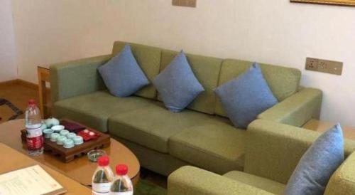 a living room with a green couch with blue pillows at Vienna Hotel Guangdong Zhaoqing Sihui Tianguangxu in Zhaoqing