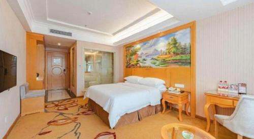 a bedroom with a large white bed and a desk at Vienna Hotel Guangdong Shantou South Bus Station in Shantou